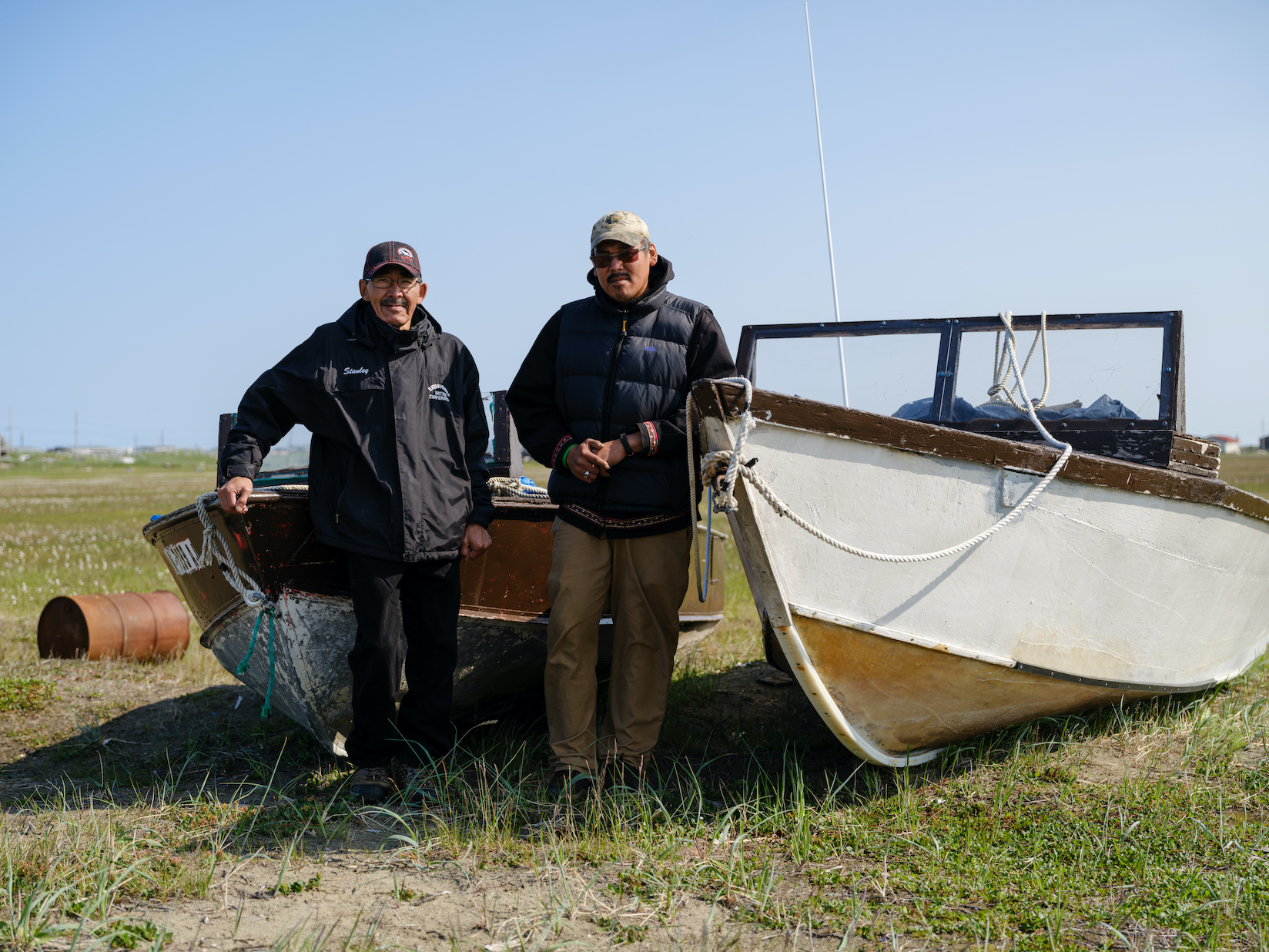 Travis and Stanley standing near two boats on land