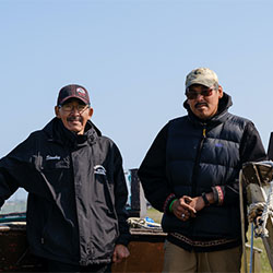 Travis and Stanley standing near two boats on land